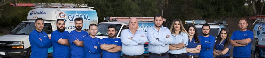 A group of professionals stands confidently in front of HVAC service vehicles, surrounded by greenery.