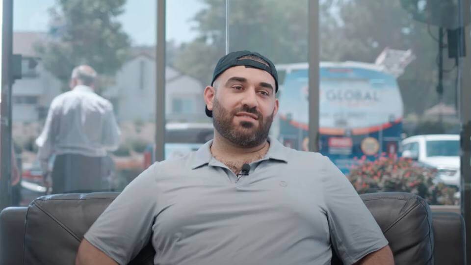 Smiling man wearing a backwards hat giving his video testimonial